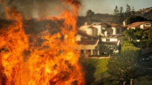 Flames rise as the Palisades Fire advances on homes in the Pacific Palisades neighborhood of Los Angeles, Tuesday, Jan. 7, 2025. (AP Photo/Ethan Swope)